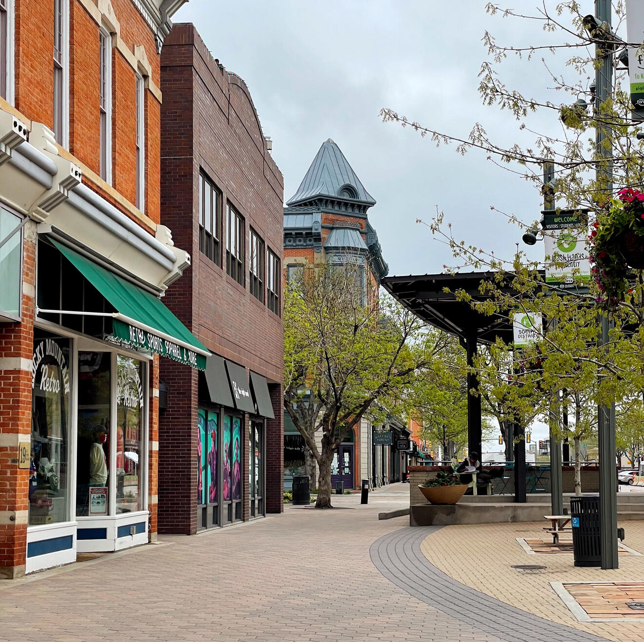 Photo of Old Town Square in downtown Fort Collins. Camera is pointed toward the stage facing northwest. Photo contains a line of storefronts on the left and the corner of the stage on the right.